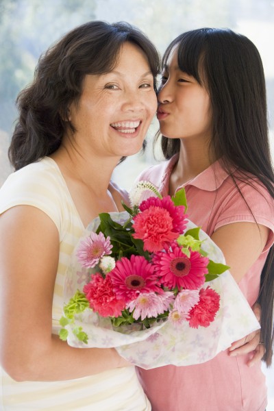 granddaughter kissing grandmother on cheek holding