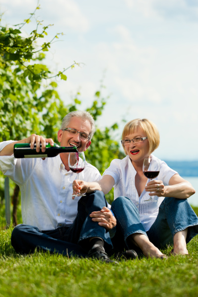happy couple drinking wine at lake