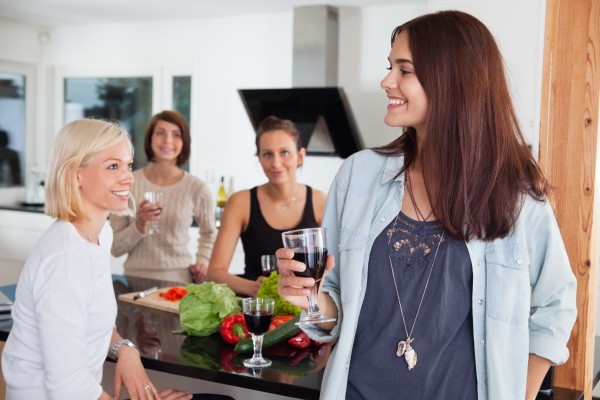 female friends enjoying drink in kitchen