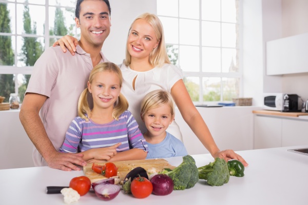 smiling posing family cutting vegetables together