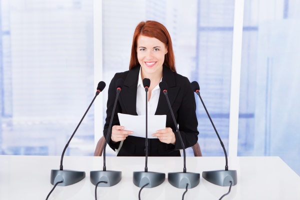 smiling businesswoman giving speech at conference