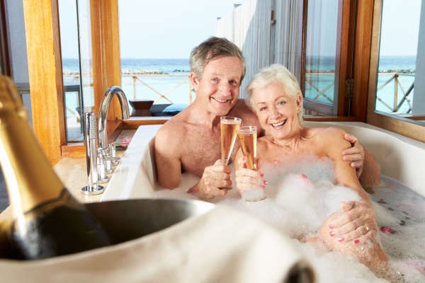senior couple relaxing in bath drinking