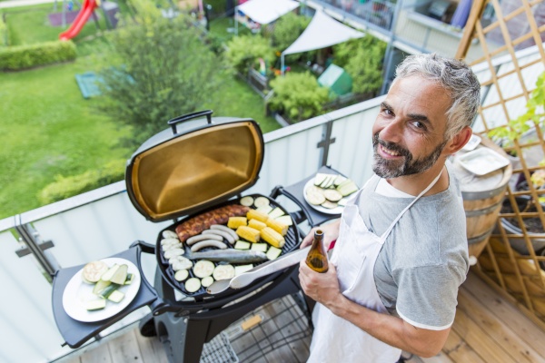 smiling man barbecuing on his balcony