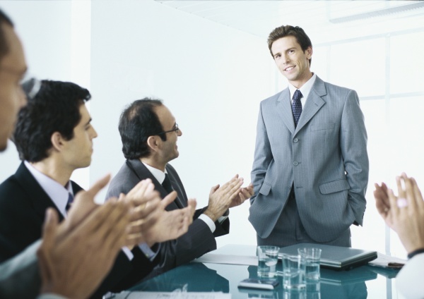 seated businesspeople applauding businessman standing at
