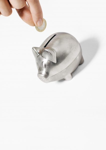 hand inserting coin into piggy bank