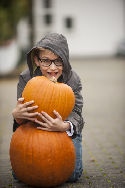 smiling boy with two big pumpkins