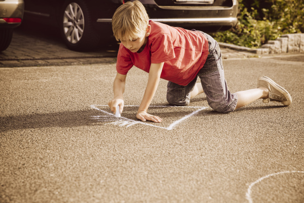 boy using sidewalk chalk in his