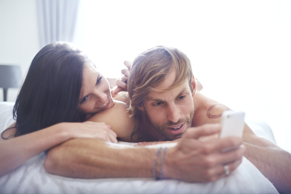 couple relaxing on bed texting with