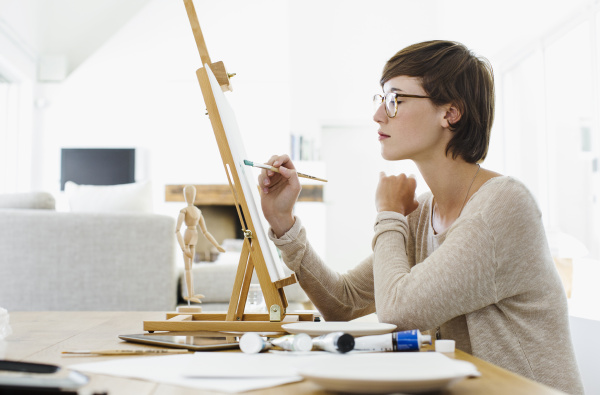 woman painting on easel at table