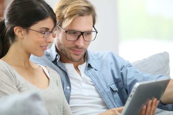 couple with eyeglasses websurfing on tablet