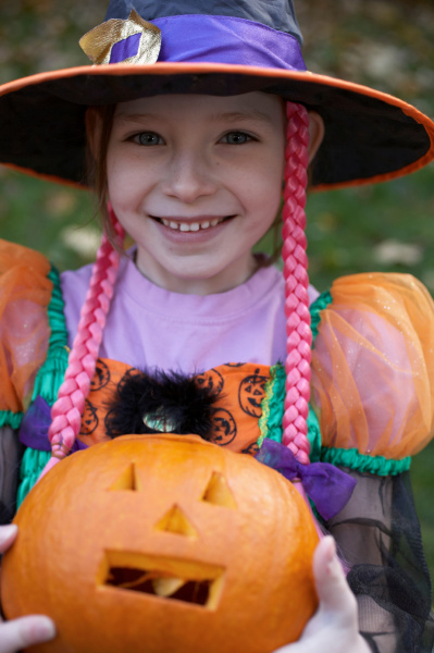 girl in halloween costume with pumpkin