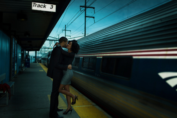 couple kissing at train station