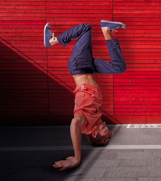 break dancer doing handstand against red
