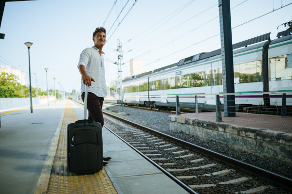 young man with suitcase waiting at