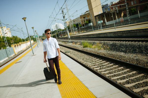 young man with suitcase walking at