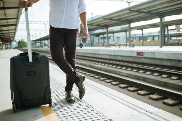 man with suitcase waiting at station