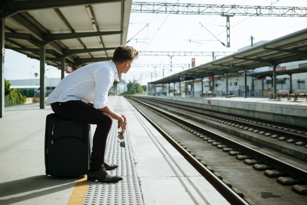 young man with suitcase waiting at
