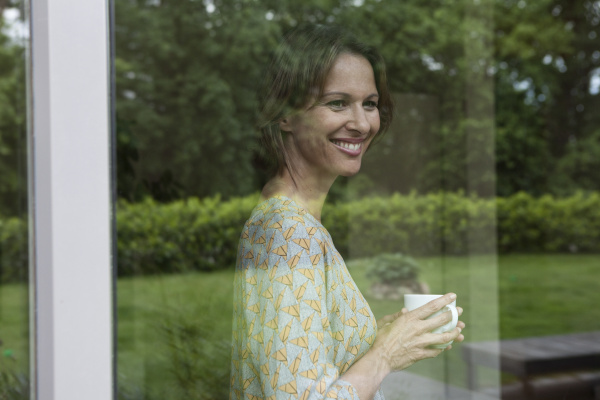 smiling woman holding cup looking out