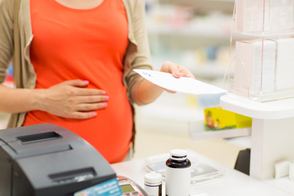 pregnant woman buying medication at pharmacy