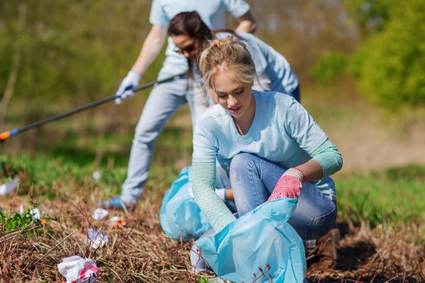 volunteers with garbage bags cleaning park