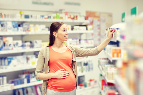 happy pregnant woman choosing medicine at