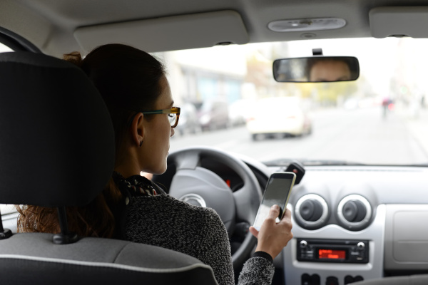 woman in car looking at smartphone