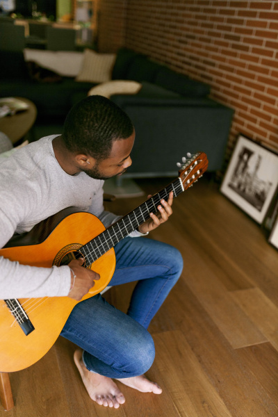 young man at home playing guitar