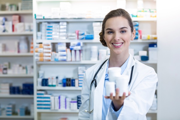 smiling pharmacist showing medicine container in