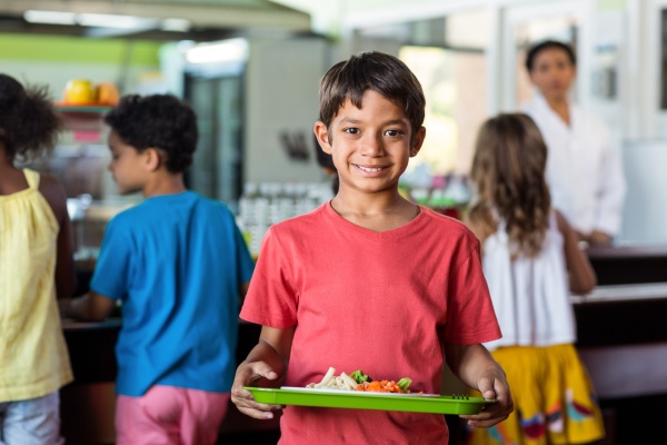 schoolboy holding food tray in canteen