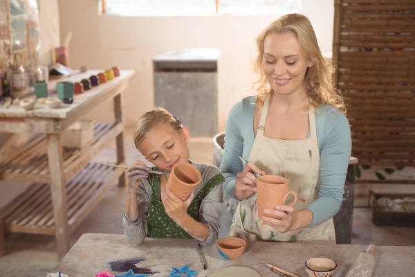 female potter and girl painting in