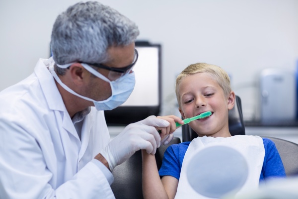 dentist brushing a young patients teeth