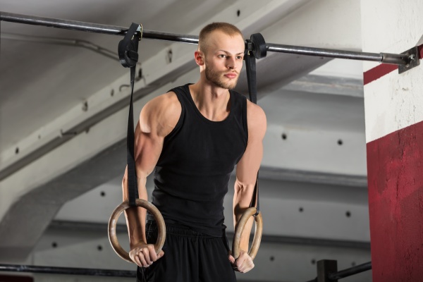 fitness man training arms with gymnastics