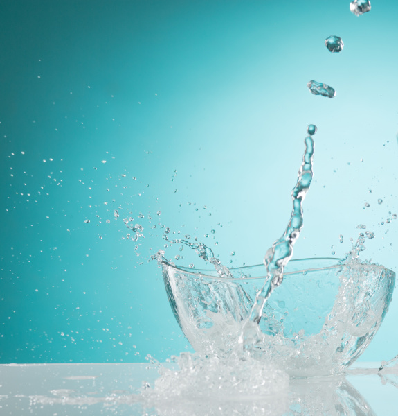 The water splashing to glass bowl on white background - Stock Photo