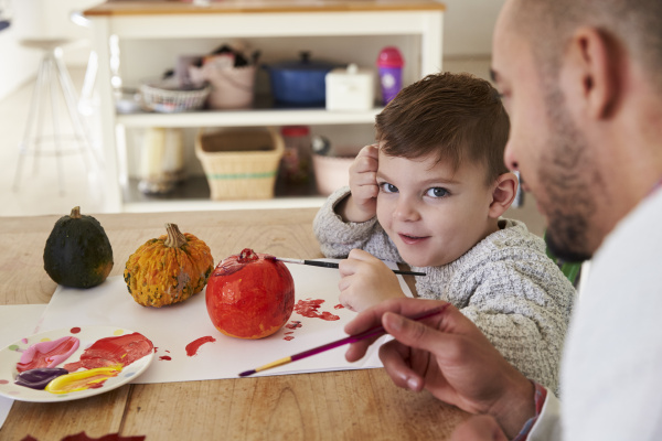 father and son decorating halloween pumpkins