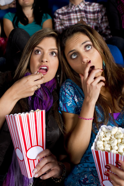 hispanic friends enjoying popcorn in movie