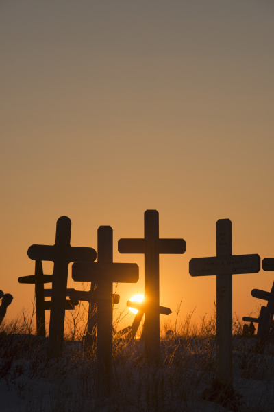 a setting sun shines through crosses