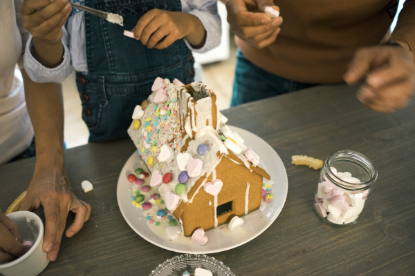family pasting gingerbread house in kitchen