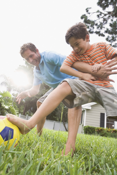 father and son playing soccer in