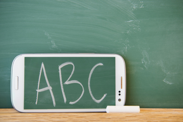 smartphone leaning against chalkboard with abc