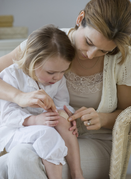mother putting bandage on daughters knee