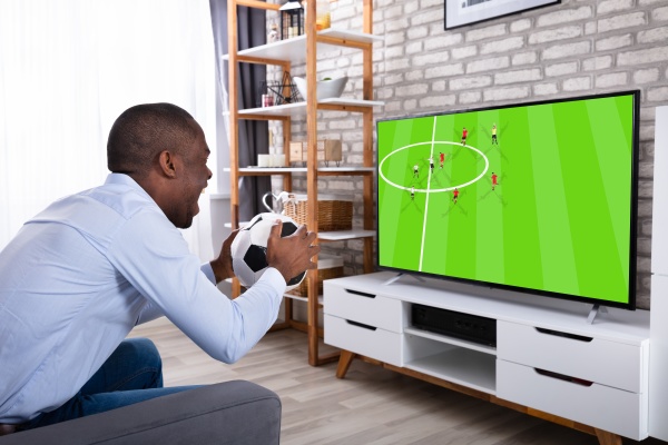african man holding ball watching television