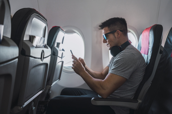 man in airplane using smartphone