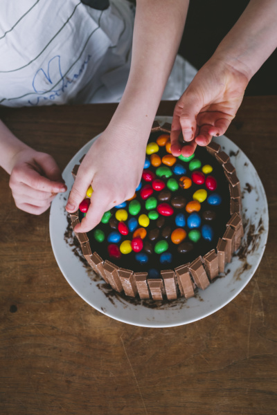 children hands decorating a cake with