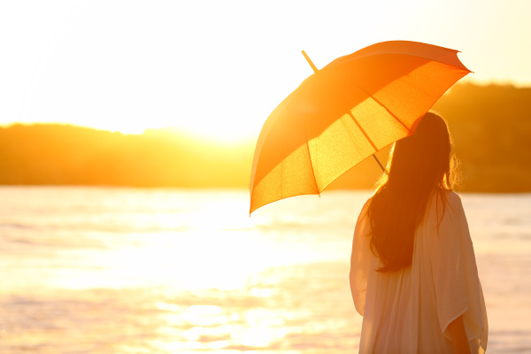 woman with umbrella at sunset on