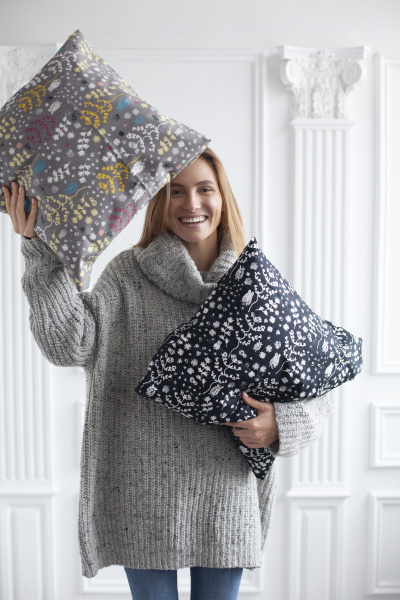 smiling woman holding patterned cushions