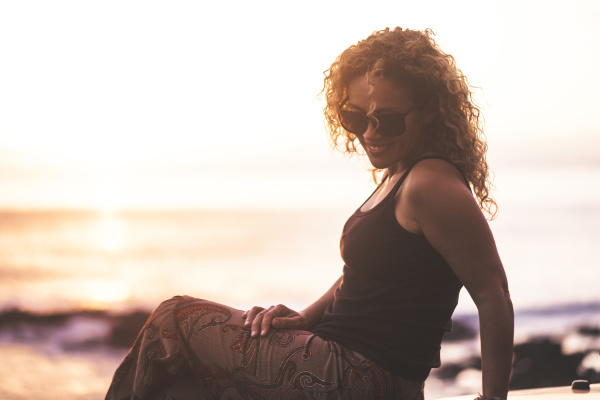 smiling woman sitting by beach at