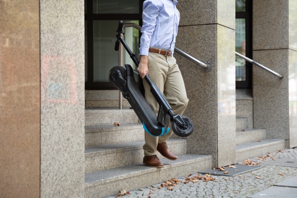 man carrying e scooter from work