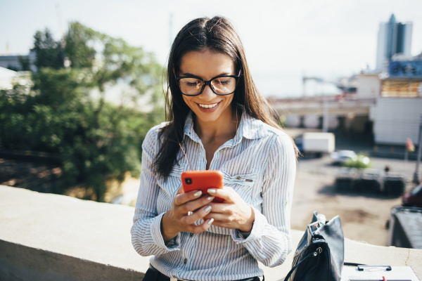 smiling young businesswoman checking cell phone