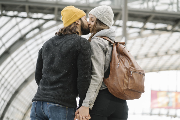 young couple kissing at the station