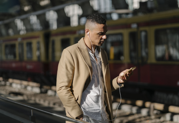 man standing at train station using